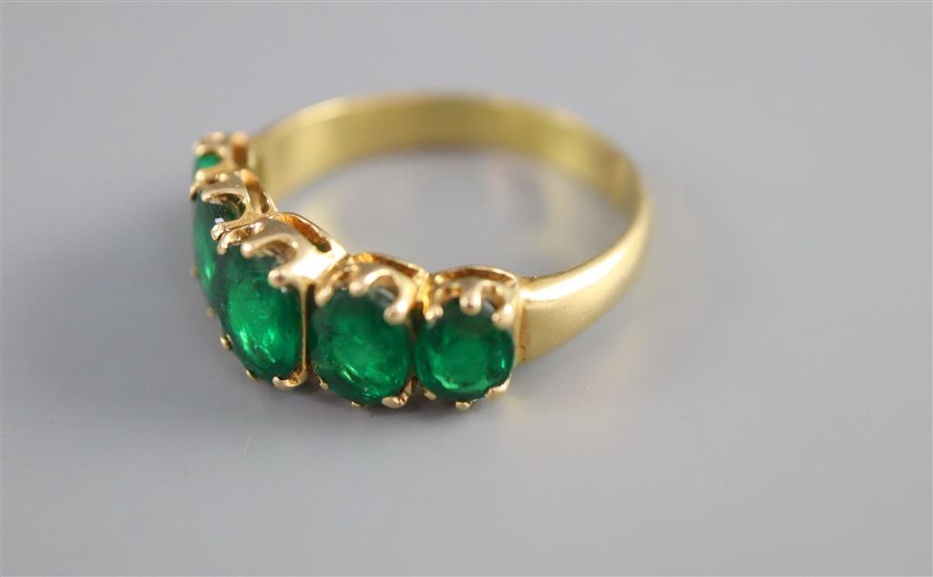 A mid to late 20th century gold and graduated five stone oval cut emerald set half hoop ring,